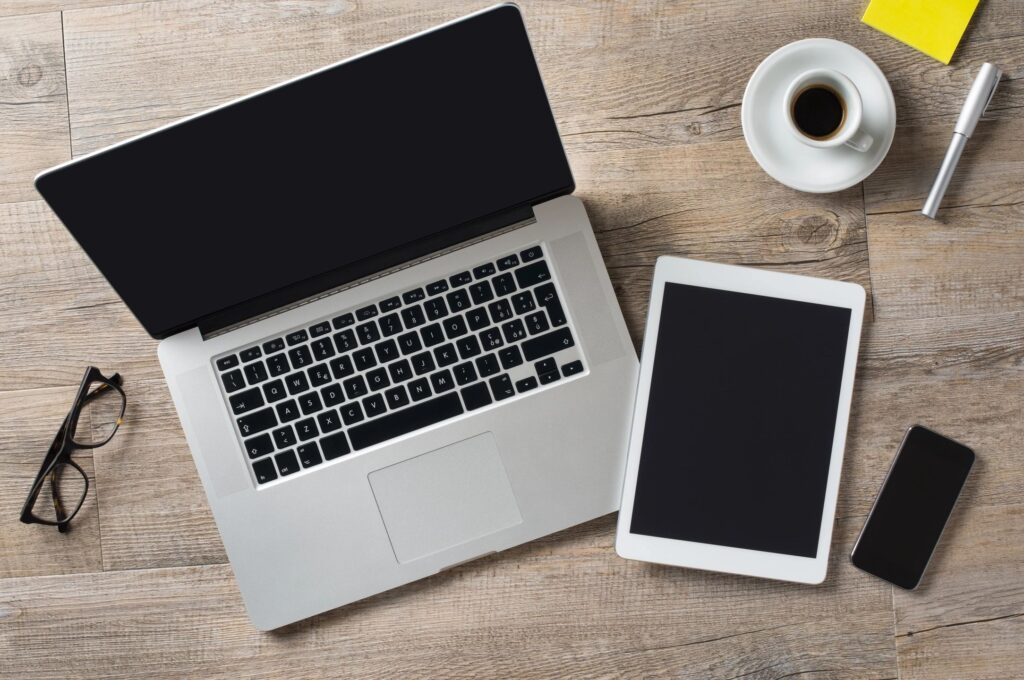 Laptop and mobile on a desk top next to a cup of coffee
