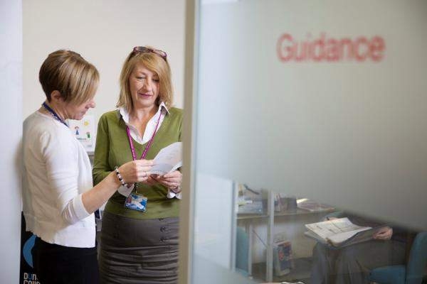 Two people looking at a leaflet a guidance office