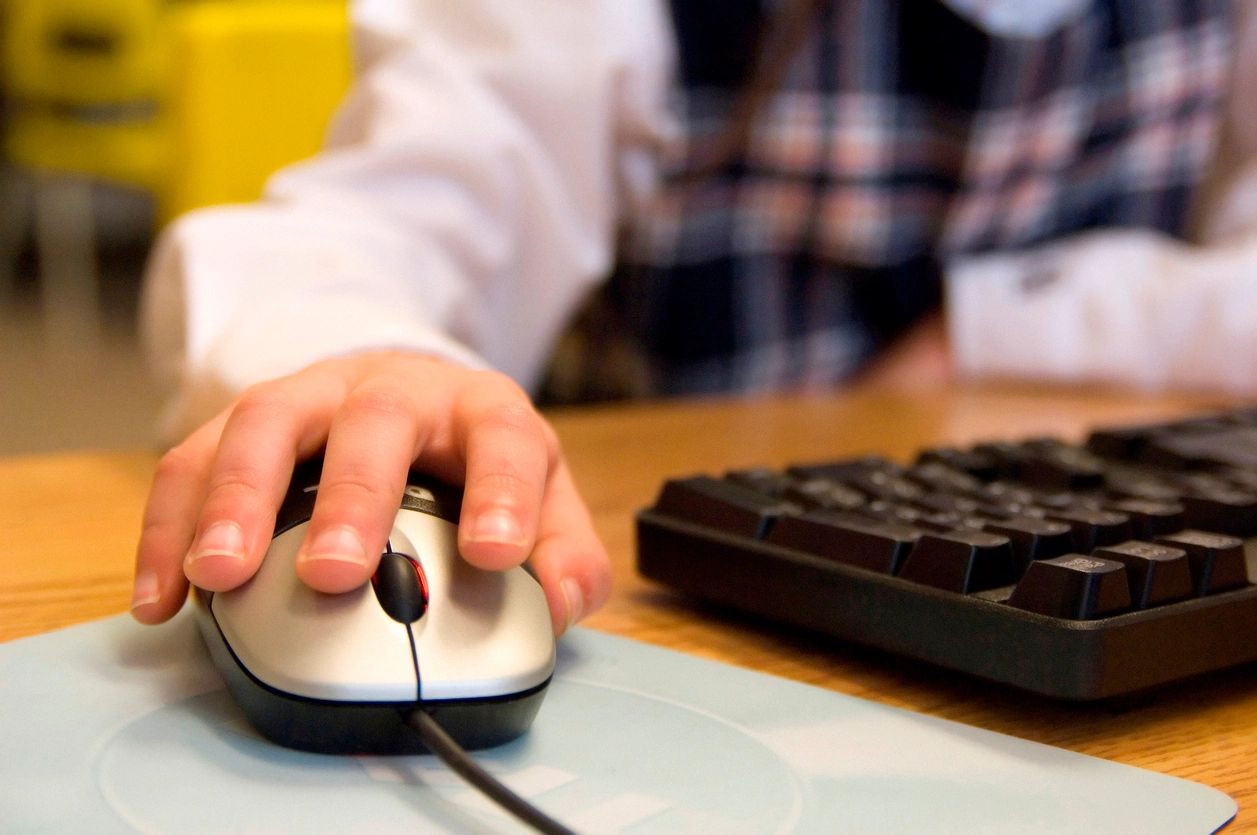 Hand on top on a mouse next to a keyboard