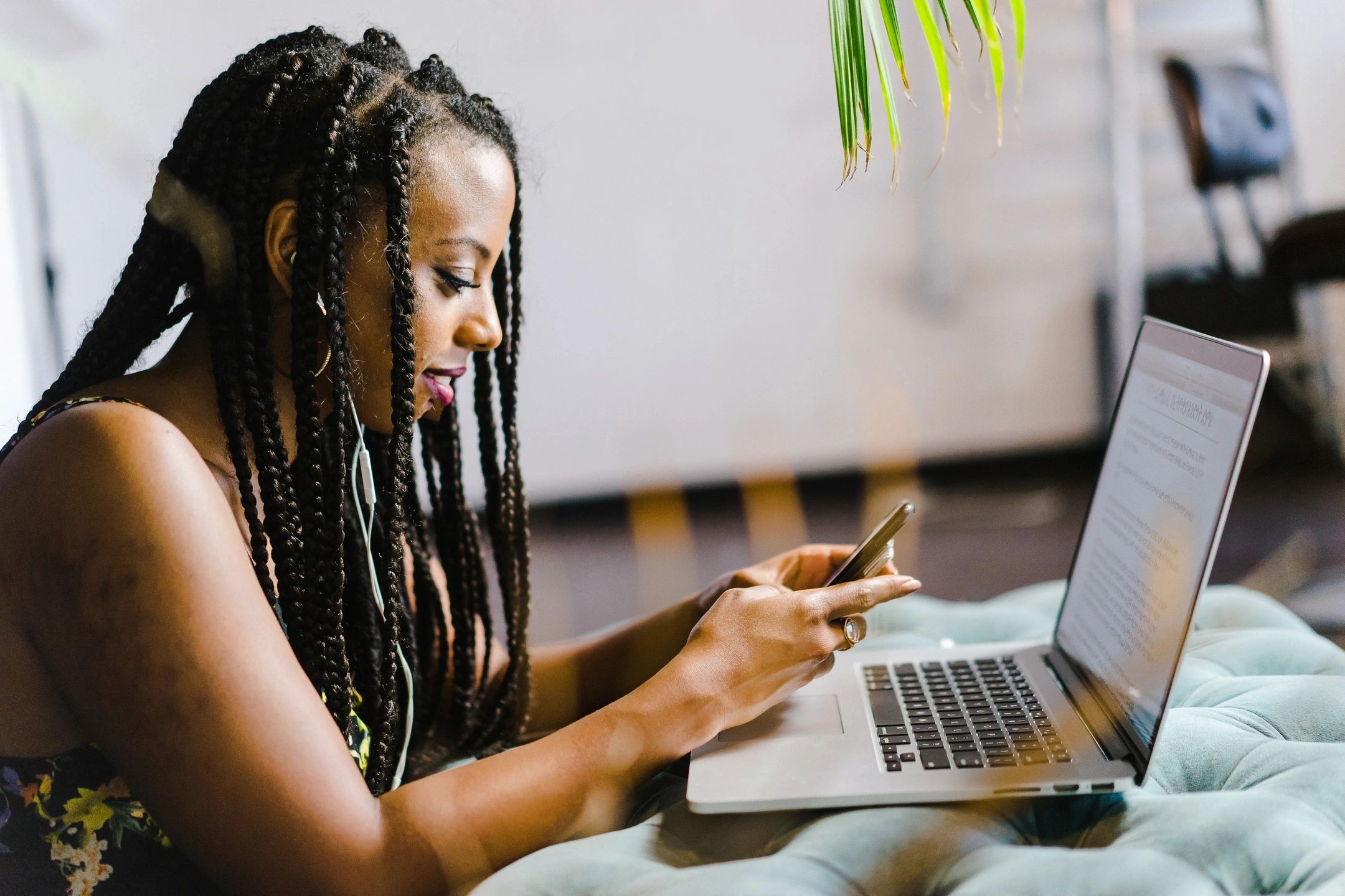 women holding mobile device with laptop on desk