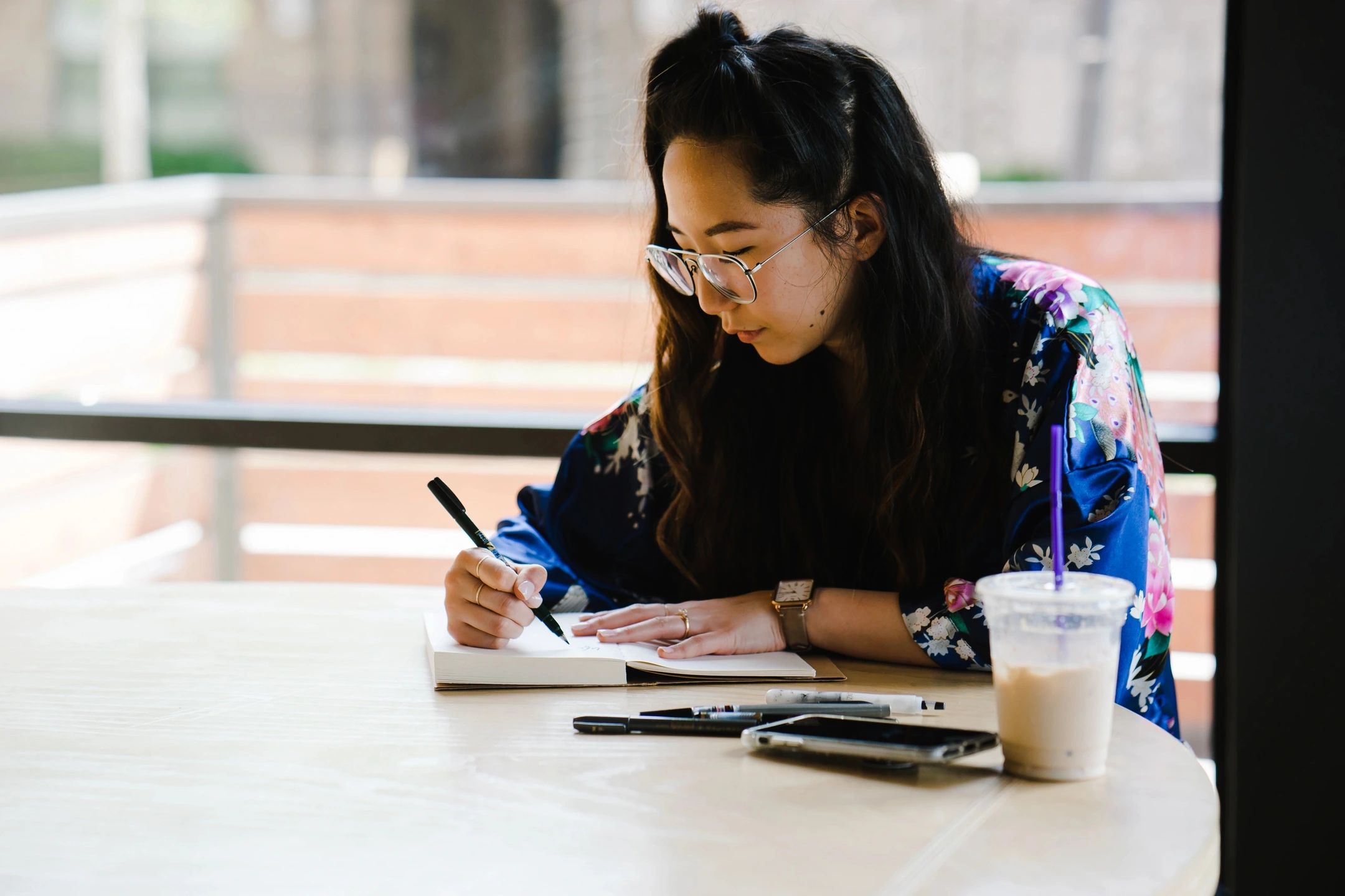 woman sitting at a desk writing in a notebook