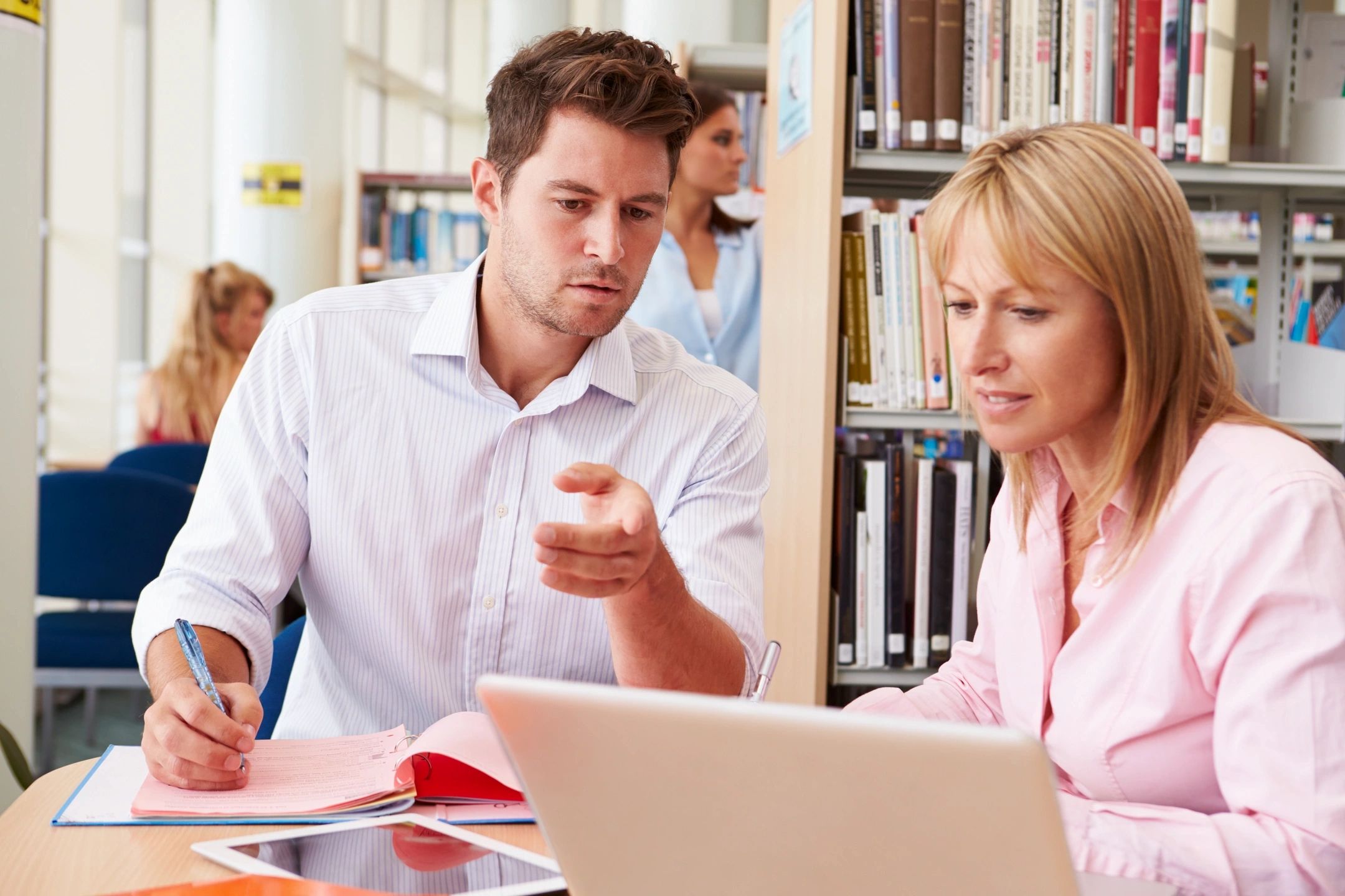 man and woman discussing at a desk with laptop