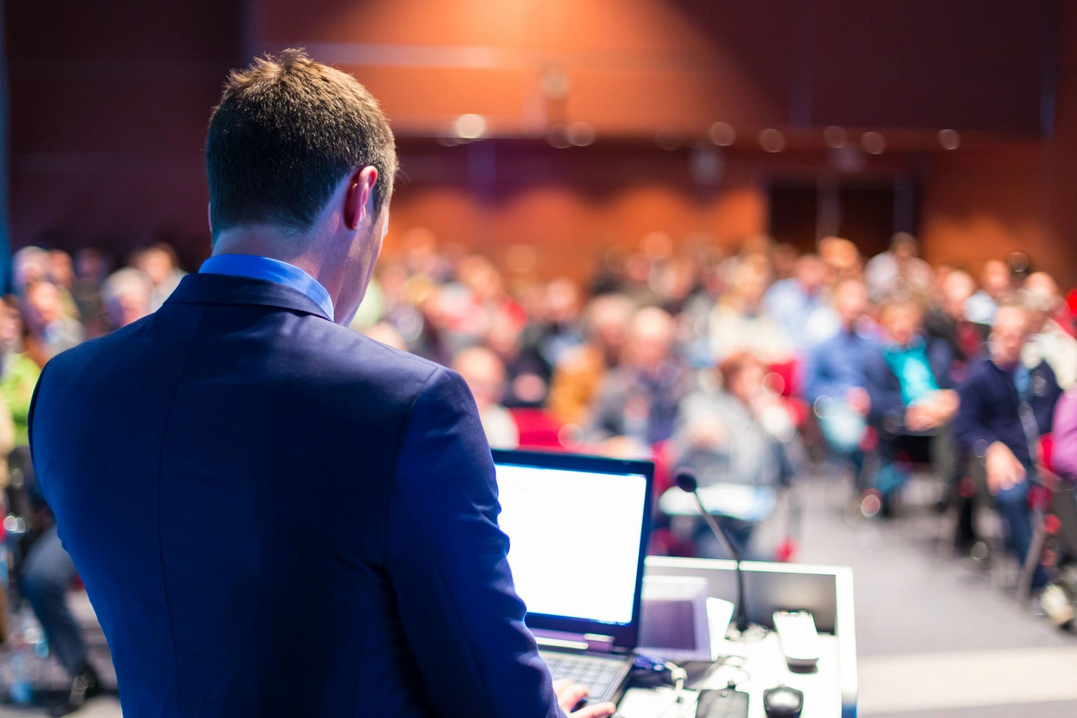 man standing at lectern talking to an audience